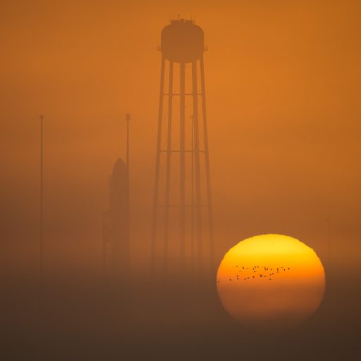 The sun rises behind the Antares rocket standing tall atop its Wallops Island Launch Pad - Photo: NASA/Bill Ingalls
