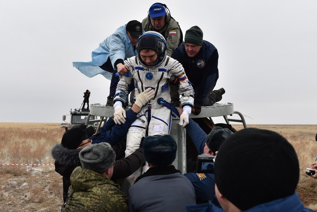Ground personnel help International Space Station (ISS) crew member Sergei Volkov of Russia to get off the Soyuz TMA-18M space capsule after landing near the town of Dzhezkazgan, Kazakhstan, on March 2, 2016. US astronaut Scott Kelly and Russian cosmonaut Mikhail Kornienko returned to Earth on March 2 after spending almost a year in space in a ground-breaking experiment foreshadowing a potential manned mission to Mars. AFP PHOTO / POOL / KIRILL KUDRYAVTSEV