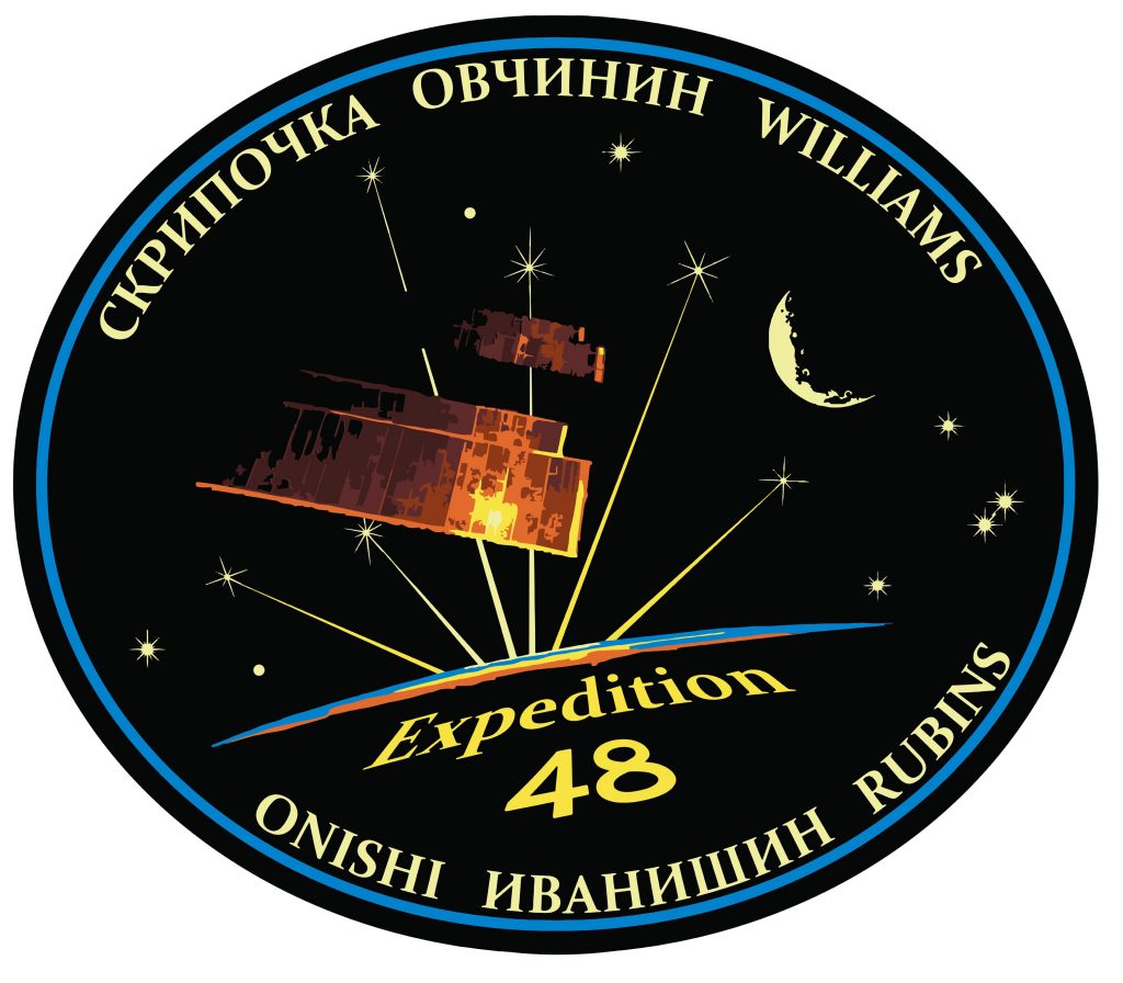 The Expedition 48 Crew Patch depicts the iconic solar arrays of the International Space Station glowing in the sunlight with a star-filled sky, the Moon and Earth's backlit limb in the background, showing the thin atmosphere protecting planet Earth. Six stars connected to the glowing sunlight represent the six Expedition 48 crew members. -- Credit: NASA